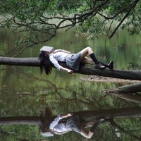 kvinne hviler mot et tre med en bok over ansiktet